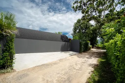 a driveway leading to a white building with a black roof at New 3BR Chalet-Style Villa Pasak Paradise 3, Private Pool, 10min drive to Laguna Phuket in Bang Tao Beach