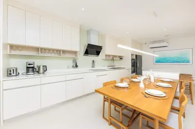 a kitchen with white cabinets and a wooden table at Luxury 3BR Villa Wallaya with Private Pool in Bang Tao Beach