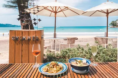 a table with a bowl of pasta and a glass of wine at Luxury Penthouse 407sqm Beachfront and private pool in Phuket Town