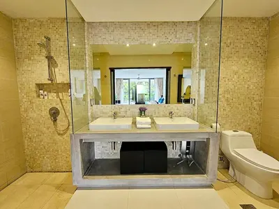 a bathroom with two sinks and a shower and a toilet at Stylish 2 Bedroom Apartment with pool access in Surin in Surin Beach