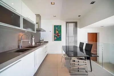 a kitchen with white cabinets and a black table at \u5361\u9a6c\u62c9\u6d77\u6ee9\u4e00\u7ebf\u6d77\u666f6\u5367\u522b\u5885 \u5df4\u4e1c\u9152\u5427\u885710\u5206\u949f\u5230\u8fbe\u76f4\u901a\u6d77\u6ee9\u5bb6\u6d77\u666fspa\u6f02\u6d6e\u8336 in Phuket Town