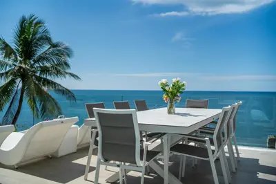 a table and chairs on a balcony with the ocean at \u5361\u9a6c\u62c9\u6d77\u6ee9\u4e00\u7ebf\u6d77\u666f6\u5367\u522b\u5885 \u5df4\u4e1c\u9152\u5427\u885710\u5206\u949f\u5230\u8fbe\u76f4\u901a\u6d77\u6ee9\u5bb6\u6d77\u666fspa\u6f02\u6d6e\u8336 in Phuket Town