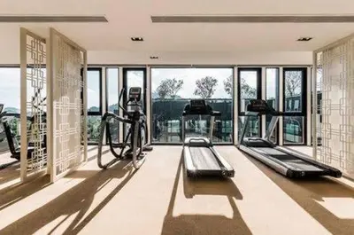 a gym with treadmills and ellipticals in a room with windows at The Base Height Condo with Rooftop infinity pool in Ban Sam Kong