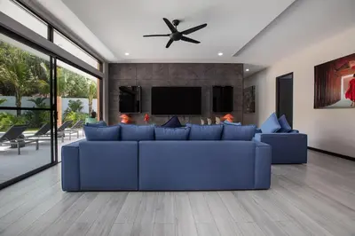 a living room with a blue couch and a tv at Stylish 4 bdrs new brand pool villa at Rawai kokmakham 1 in Rawai Beach