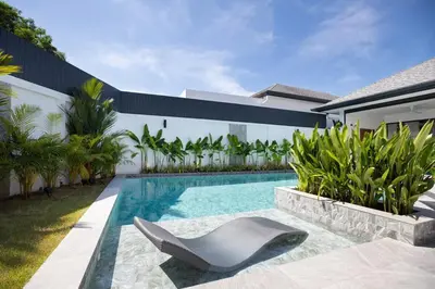 a swimming pool with a chair in front of a house at Superb 3-bedrooms pool villa in Rawai, Naiharn villa Moana in Rawai Beach