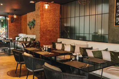 a restaurant with tables and chairs and a brick wall at Solara Stays Phuket in Bang Tao Beach
