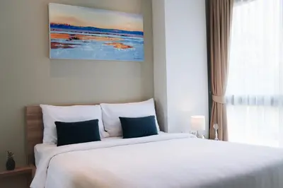 a bedroom with a large white bed with blue pillows at Solara Stays Phuket in Bang Tao Beach