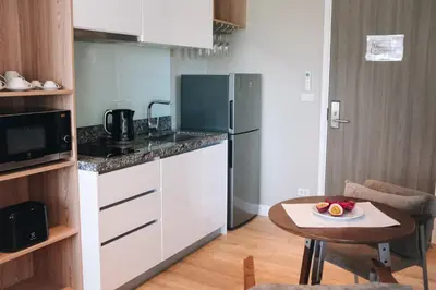 a kitchen with a refrigerator and a table with a bowl of fruit at Solara Stays Phuket in Bang Tao Beach