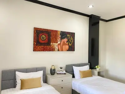 two beds in a bedroom with a painting on the wall at Wink City 4th Patong in Patong Beach