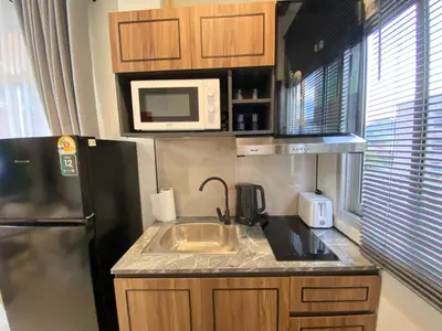 a kitchen with a sink and a black refrigerator at Wink City 4th Patong in Patong Beach