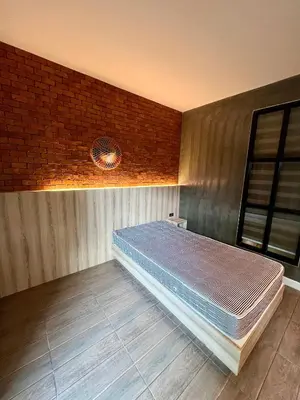 a bed in a room with a brick wall at Bang Tao cozy studio in Ban Thalat Choeng Thale