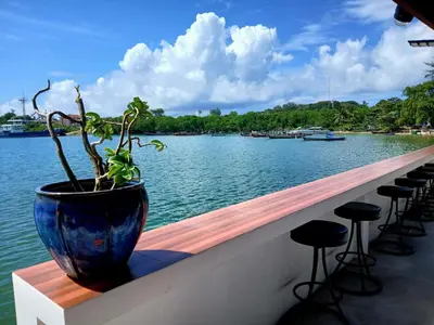 a potted plant sitting on a wall next to the water at Water's Edge Resort , in Panwa Beach