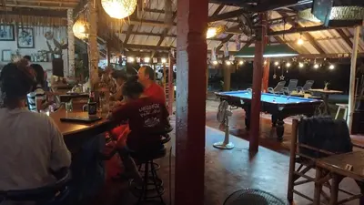 a group of people sitting at a bar with a pool table at Water's Edge Resort , in Panwa Beach