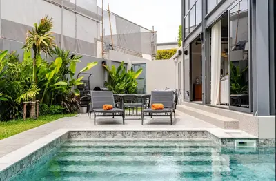 a pool with chairs and a table next to a house at Stylish Mansion for Leisure with Garden & Pool in Laguna Phuket