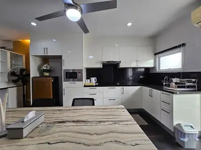 a kitchen with white cabinets and a large wooden table at Modern 3-Bedroom Townhome in Kamala in Kamala Beach