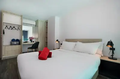 a bedroom with a large white bed with red pillows on it at Poolside Duplex In Nai harn UTL A102 in Rawai Beach