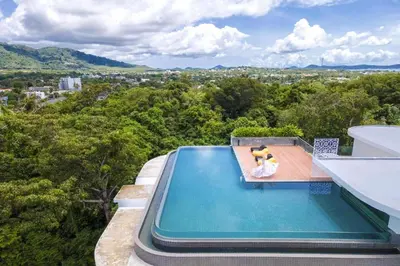 a person sitting on a chair next to a swimming pool at Poolside Duplex In Nai harn UTL A102 in Rawai Beach