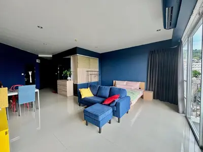 a living room with a blue couch and a table at Stylish Sea view Chic condo in Karon Beach
