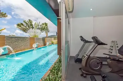 a fitness room with a swimming pool and exercise equipment at Stylish Sea view Chic condo in Karon Beach