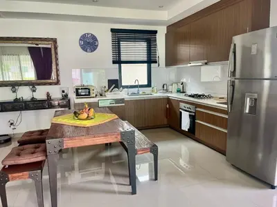 a kitchen with a table and a stainless steel refrigerator at Stunning 2-Bedroom Pool Villa in Ban Thalat Choeng Thale