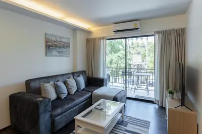 a living room with a black leather couch and a balcony at Rawai beach 1br apartment at The Title in Rawai Beach