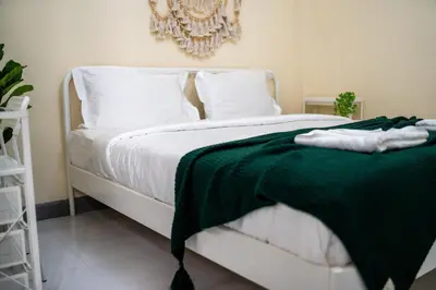 a white bed with a green blanket on it at Beachfront 4-BR House in Patong in Patong Beach