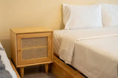 a bed with a wooden night stand next to a white bed at Beachfront 4-BR House in Patong in Patong Beach