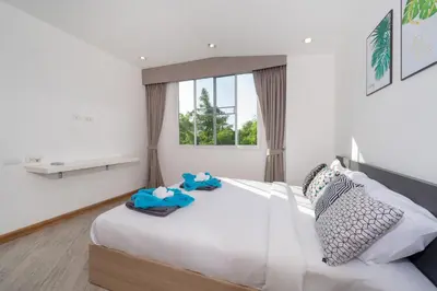 a bedroom with a large white bed with towels on it at AP Nest Villas Residence - Tropical Pool Access, near Kamala Beach in Kamala Beach