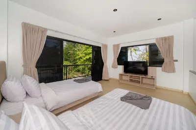 a living room with two beds and a television at The Hideout Beachfront in Patong Beach