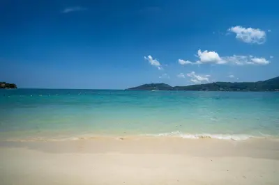 a beach with the ocean and mountains in the background at The Hideout Beachfront in Patong Beach