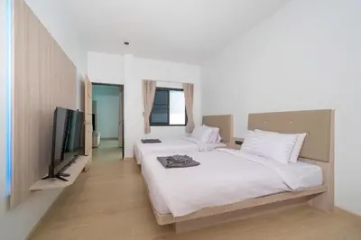 a bedroom with two beds and a flat screen tv at The Hideout Beachfront in Patong Beach