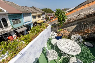 a balcony with tables and chairs on a building at Twelve 8 Boutique House in Phuket Town