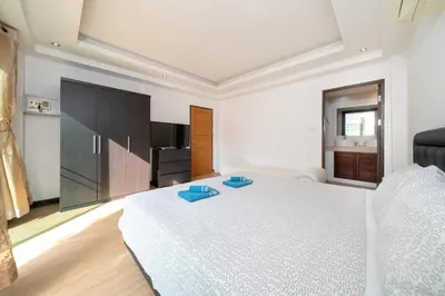 a bedroom with a large white bed and a kitchen at Jungle Villa-private pool, BBQ near Kamala beach in Kamala Beach