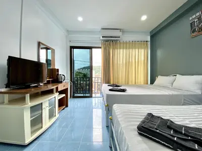 a hotel room with two beds and a flat screen tv at Mini Thai Guesthouse Patong in Patong Beach