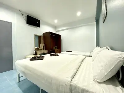 a large white bed in a room with a television at Mini Thai Guesthouse Patong in Patong Beach