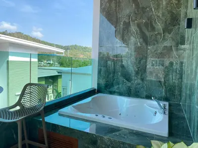 a bath tub in a bathroom with a chair at Mountain breeze villa phuket in Ban Bang Khu