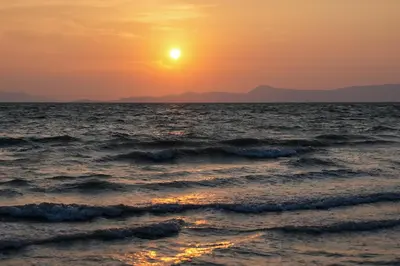 a sunset over the ocean with waves at Phuket Moonlit Bay Seaview Resort & Spa in Phuket Town