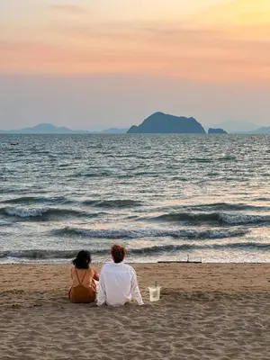 two people sitting on the beach looking at the ocean at Phuket Moonlit Bay Seaview Resort & Spa in Phuket Town