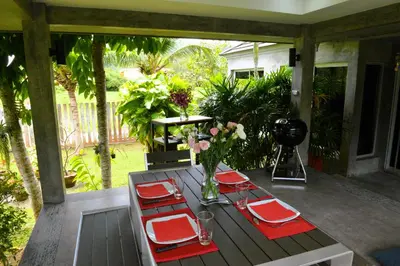 a wooden table with red napkins and flowers on a porch at 11 - Peaceful Escape on Naiyang Beach in Nai Yang Beach