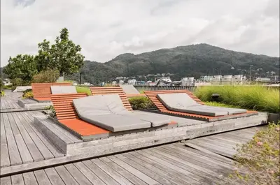 a group of chairs on a deck with a mountain at Patong city-center pool cozy condo in Patong Beach