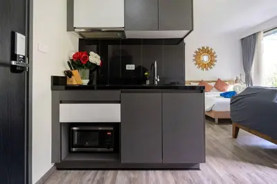 a kitchen with a stove top oven next to a living room at Patong city-center pool cozy condo in Patong Beach