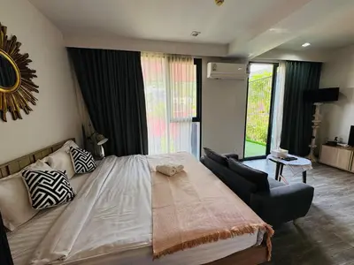 a bedroom with a large bed and a chair at Patong city-center pool cozy condo in Patong Beach