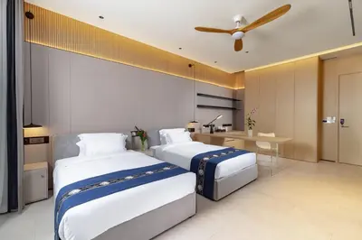 two beds in a hotel room with a ceiling fan at The Aquila Villa in Kamala Beach
