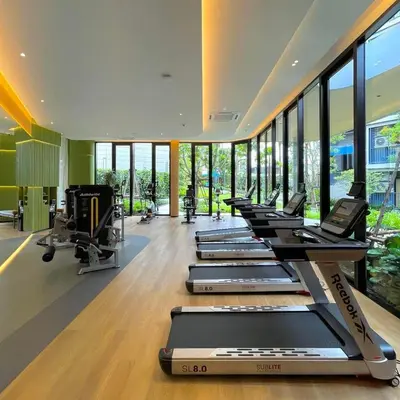 a row of treadmills in a gym with windows at Dcondo reef 99 in Kathu
