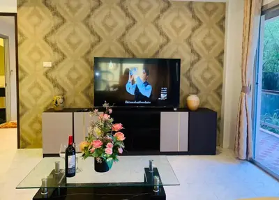 a living room with a television and a table with flowers at Rawai Condominium By Wijitra in Phuket Town