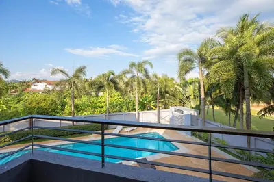 a balcony with a swimming pool and palm trees at Blissful Living & Tropical Vibes - 3BR Pool Access Villa Argent 9, just 15 min drive from Nai Yang and Nai Thon Beaches in Thalang