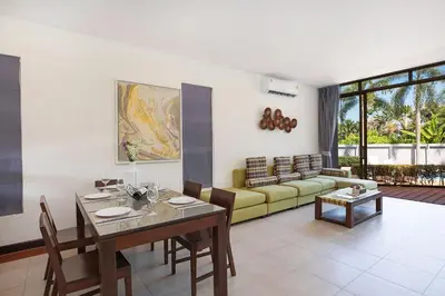 a living room with a table and a yellow couch at Blissful Living & Tropical Vibes - 3BR Pool Access Villa Argent 9, just 15 min drive from Nai Yang and Nai Thon Beaches in Thalang