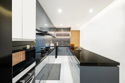 a kitchen with a black counter top and white cabinets at MANDLA VILLAS COLLECTION, White Anda Naiharn in Rawai Beach