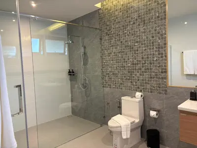 a bathroom with a toilet and a glass shower at MANDLA VILLAS COLLECTION, White Anda Naiharn in Rawai Beach
