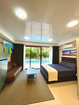 a bedroom with a bed and a couch and a pool at Palm Breeze View in Ban Mai Salae